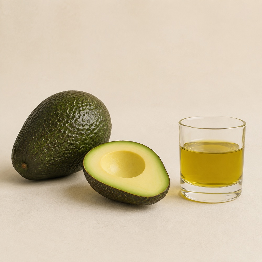 Avocado oil streaming from a squeezed avocado half into a glass bowl